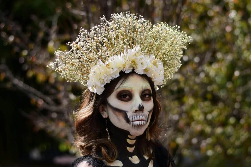 Woman with skeletal makeup and a floral crown, Day of the Dead celebration.
