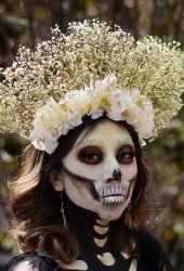 Woman with skeletal makeup and a floral crown, Day of the Dead celebration.