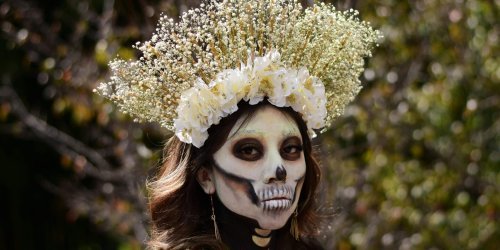 Woman with skeletal makeup and a floral crown, Day of the Dead celebration.