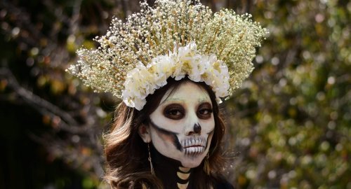 Woman with skeletal makeup and a floral crown, Day of the Dead celebration.